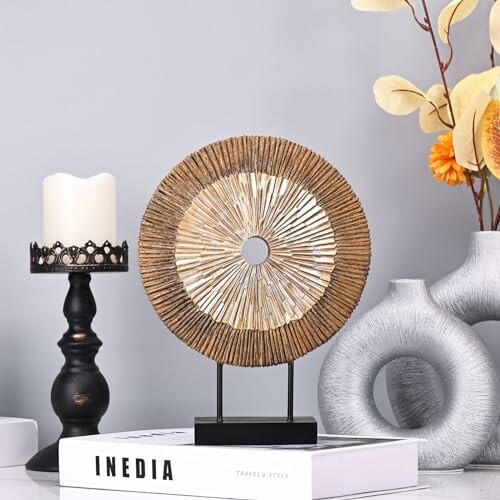 Decorative round sculpture, candle, and vases on a table