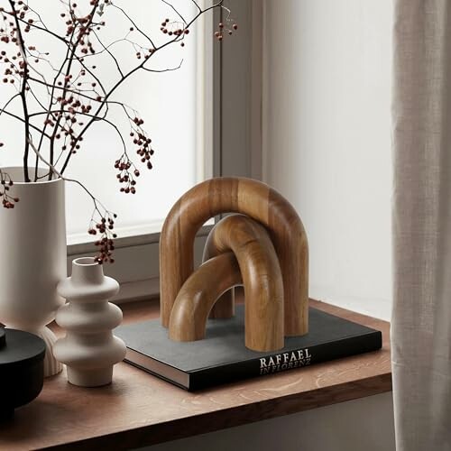 Modern wooden sculpture on windowsill with vases and branches.