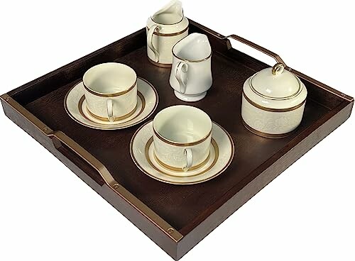 Vintage tea set with cups, saucers, creamers, and sugar bowl on a wooden tray.