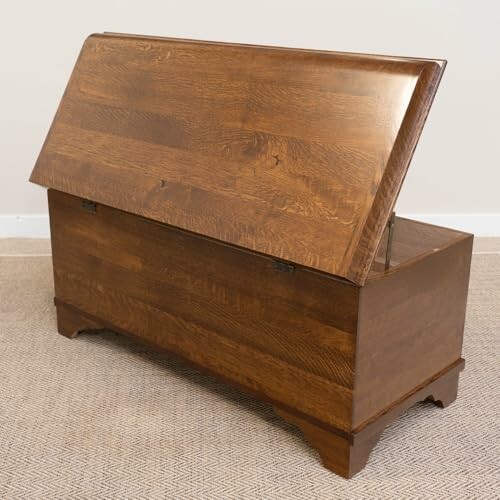 Open wooden blanket chest on carpeted floor.