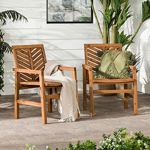 Two wooden patio chairs with cushions and a throw blanket